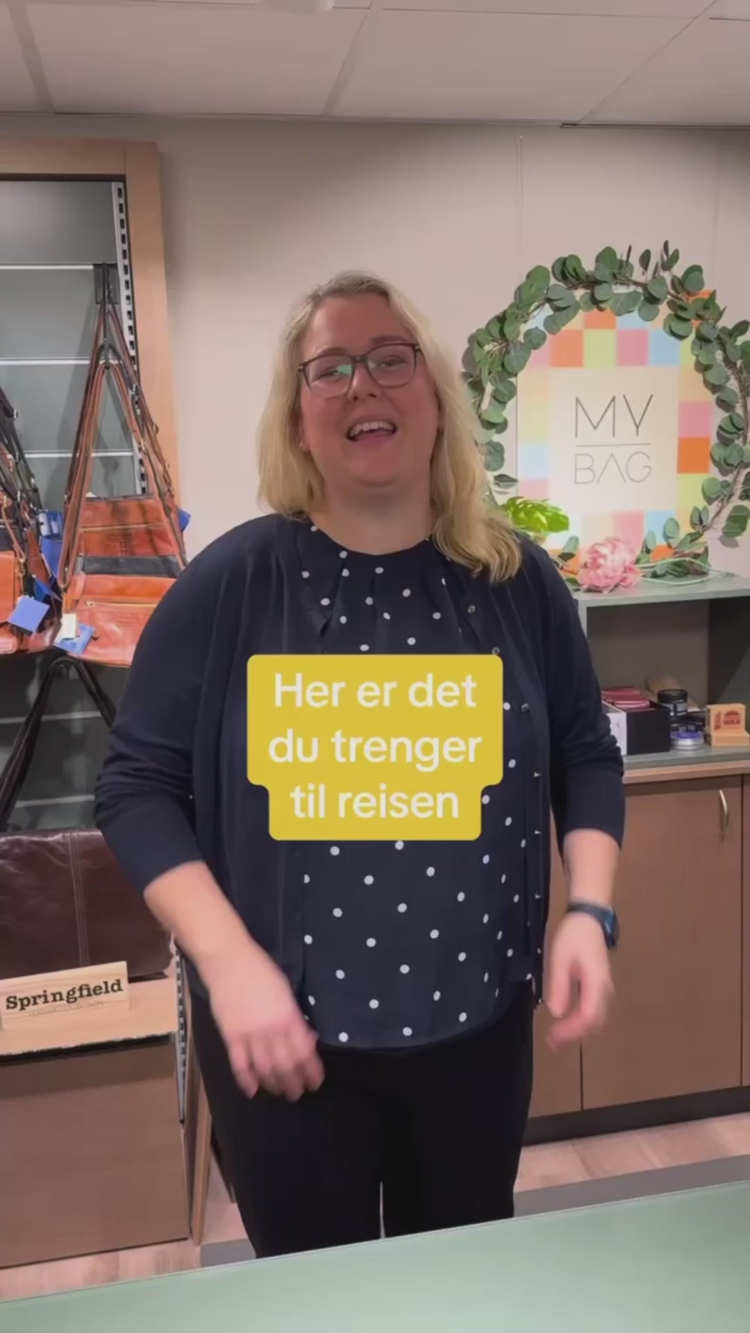 video av en dame som jobber i butikk og som forteller nødvendighetere av reisetilbehør en bør ha med seg på reisen, som nakkeputer, flaskesett, sovemaske, toalettmappe, bag og pakkeposer