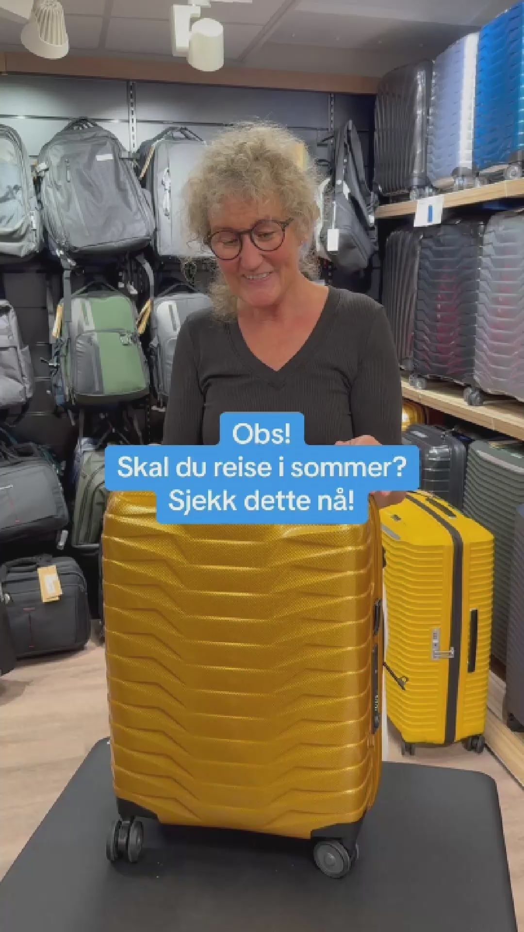 dame som jobber i butikk og demonstrerer hva en må lete frem dersom en trenger å bestille nye deler til en Samsonite koffert. I bakgrunnen er det kofferter plassert i hyller, og en vegg med ryggsekker. 