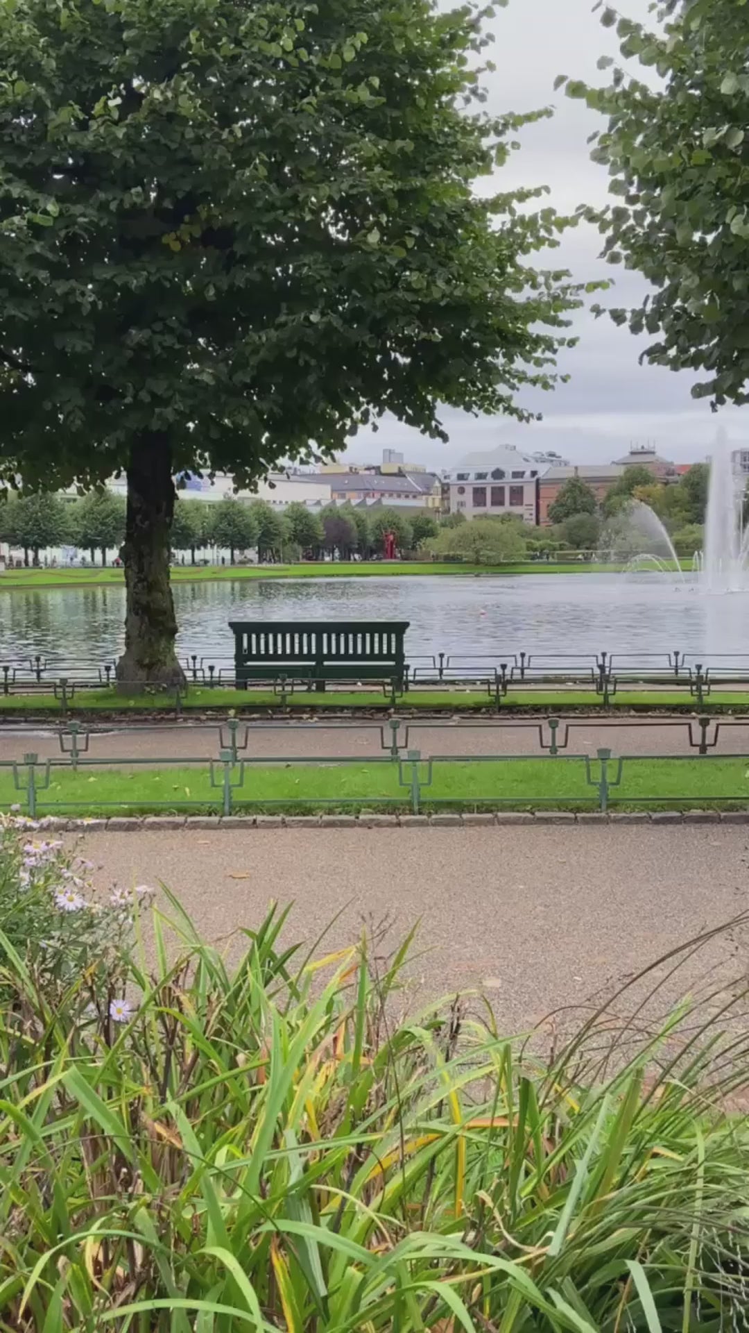 dame som går ute i en park med en beige day et skulderveske på skulderen